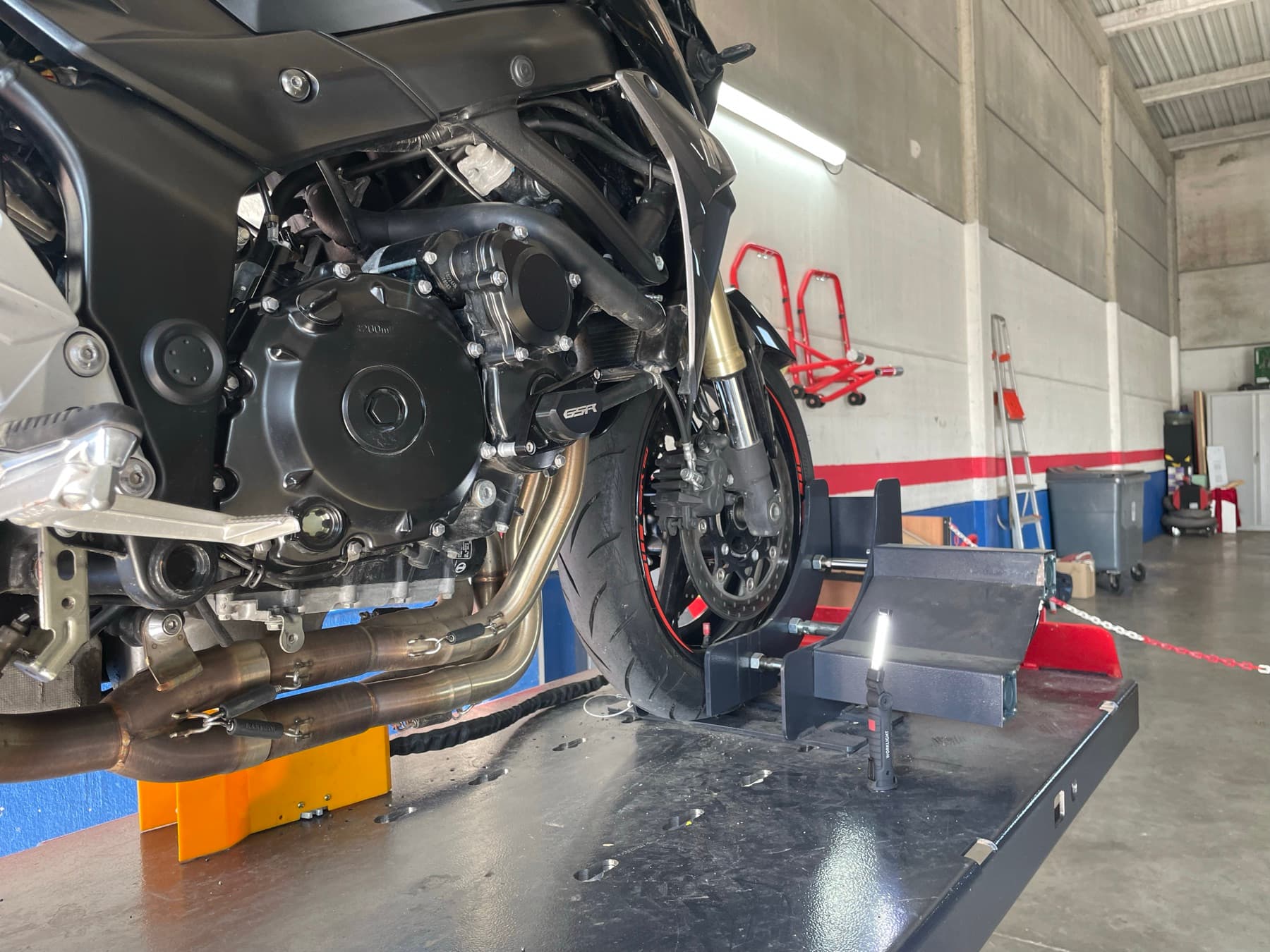 Moto positionnée sur le banc de contrôle, ligne d'échappement et partie cycle accessibles à l'inspection