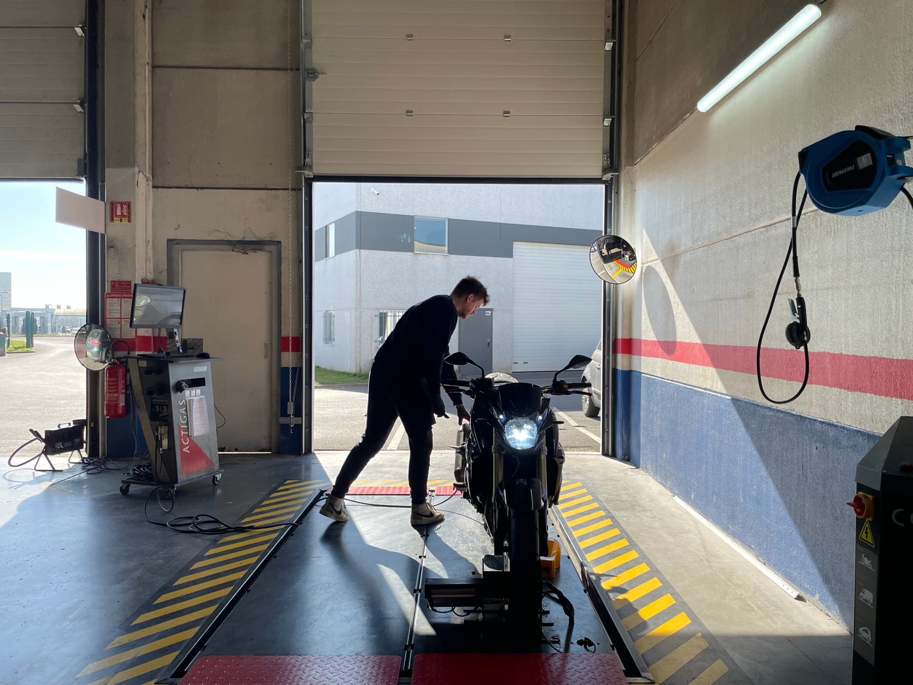 Vue d'ensemble de la piste de contrôle technique catégorie L, une moto positionnée sur le banc